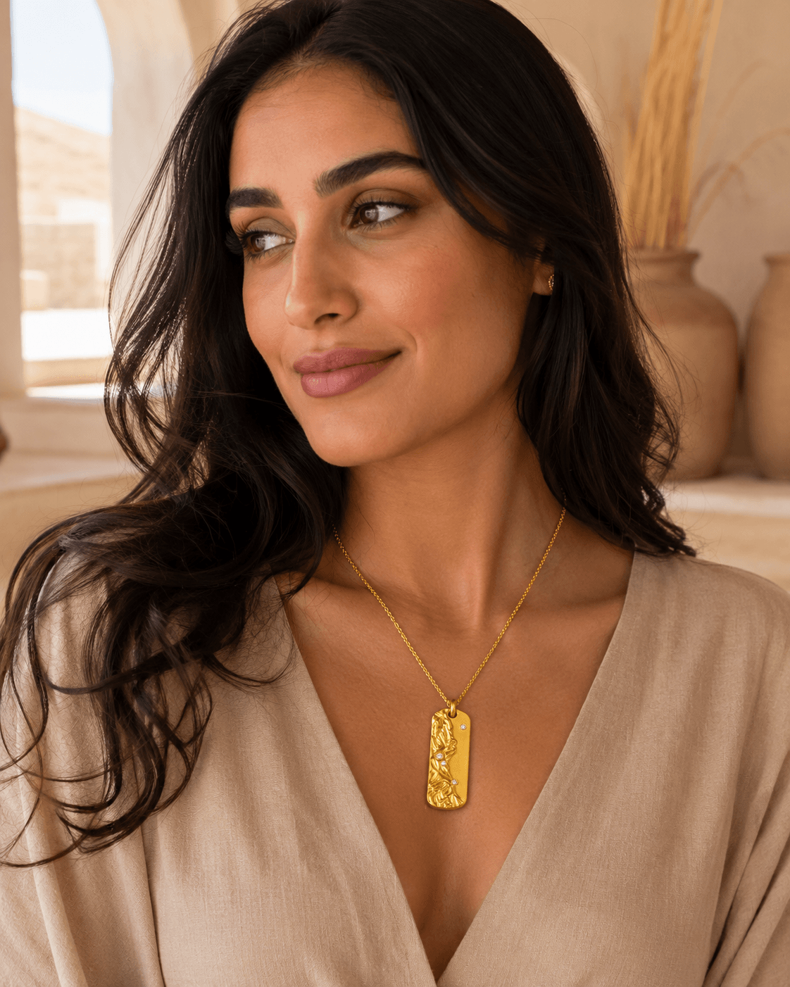 Middle Eastern woman wearing the Metal Element Gold Pendant Necklace in a beige outfit